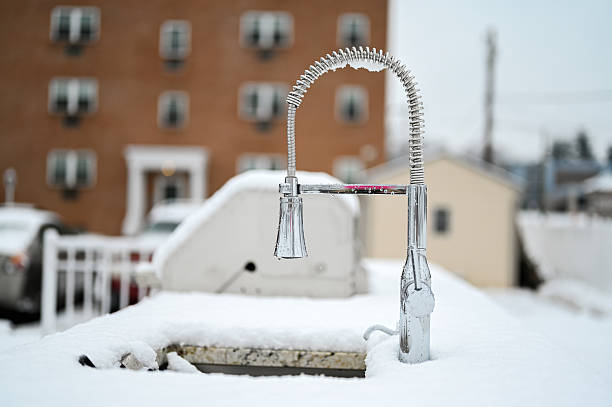 Outdoor stainless steel faucet resting on a snowy countertop on a cold winter day