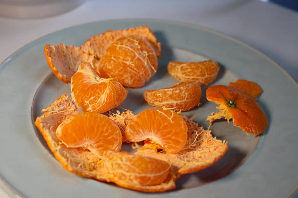 peeled mandarin orange segments with peel on a plate. fruit design element or banner.