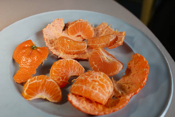 a peeled mandarin orange on a plate, isolated on a table. fruit design element.