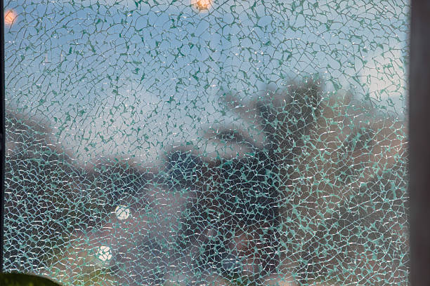Abstract close up view of broken tempered glass creating an irregular cracked texture with light reflections, transparent layers and copy space, suitable for concepts such as damage, fragility, security, risk, accident, abstract background and design use