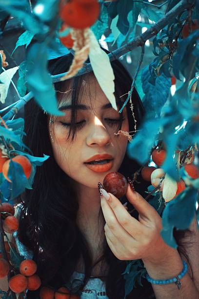 Beautiful woman eats a plum next to the tree
