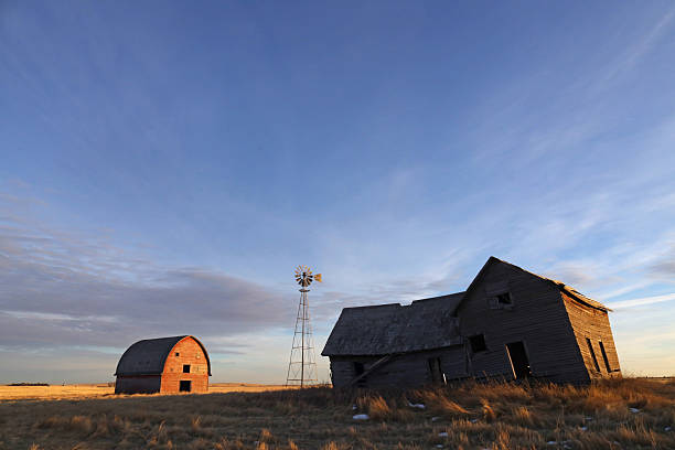 Abandoned Shed and Grain Silo Behind a Barbed Wire Fence.  No Shooting Graffiti written on the grain Silo.  Brown, dried prairie  in spring or autumn.