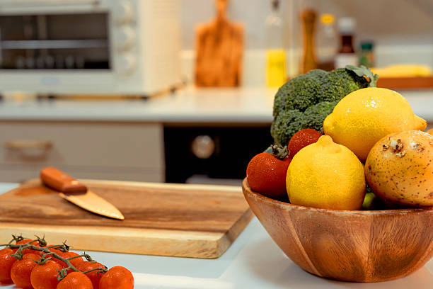 Empty kitchen with vegetables and a cutting board laid out on the table for cooking.