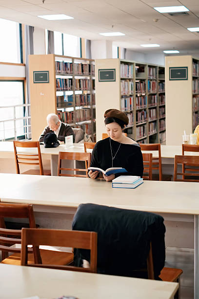 Female student browsing a library, reading books and looking for study materials. Real student lifestyle moment showing everyday education and academic routine in New York.