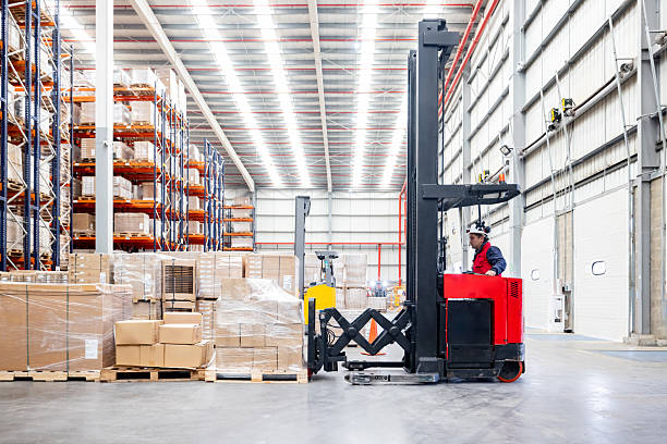 Latin American employee driving a forklift and moving boxes at a distribution warehouse