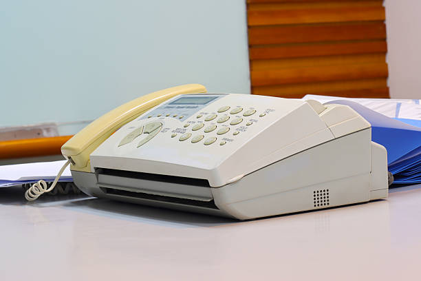 A fax machine on a desk with paper loaded, ready to send documents in an office setting