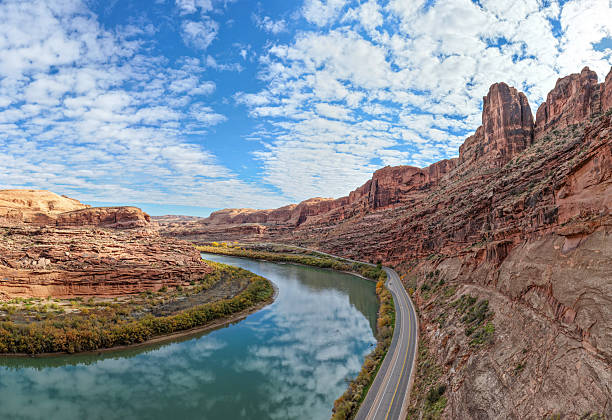 A breathtaking view of UT-128 near Moab, Utah, where the highway curves alongside the Colorado River through towering red rock canyons. A stunning example of the American Southwest’s rugged natural beauty.