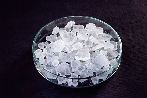 Abstract of woman hand pick up cube of ice in to glass water with light and shadow on white table background. Tooth sensitive ice cause of pain.