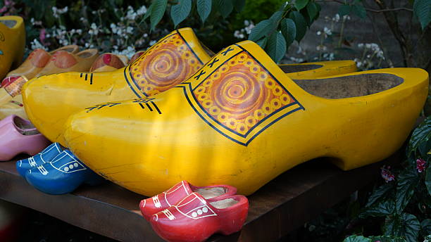 Pair of red wooden shoes hanging on an old dark wooden wall. Traditional alpine decoration symbolizing Swiss heritage and craftsmanship.