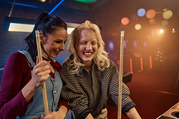 Two girls friends playing pool