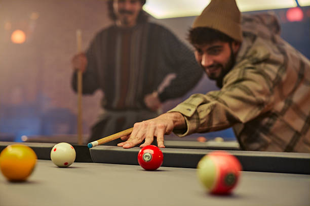 Playing Russian billiards on a green table. A white ball falls into the corner pocket. Top view. A successful shot close up. Pastime at home playing sport game hobby.