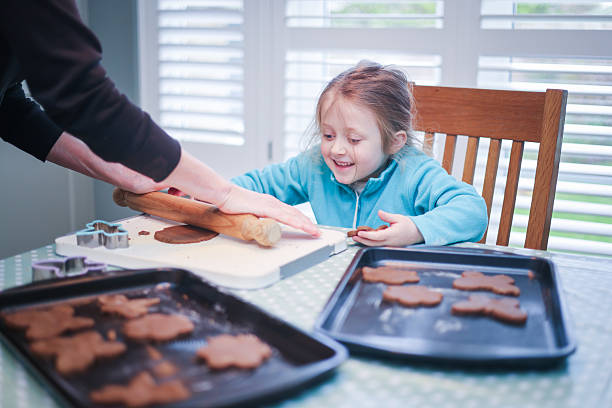 Five year old girl preparing and making Gingerbread shapes with her Grandmother at a domestic kitchen table