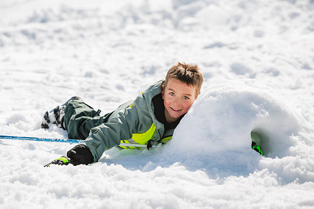 Male man in winter clothes lies down in soft white snow. Young male man makes snow angel on white snow, on frozen lake. Lifestyle full length portrait.
