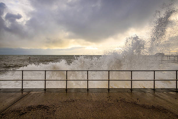 Crashing waves and dramatic sky with promenade railings
