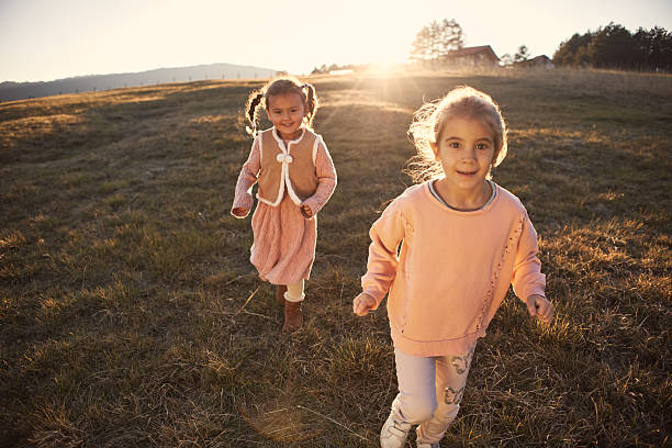 Happy kids playing in nature on sunset. It’s beautiful autumn day.