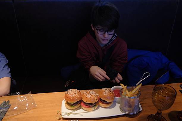 12 year old boy enjoying mini burger set in a cafe, fast food, weekend pleasure