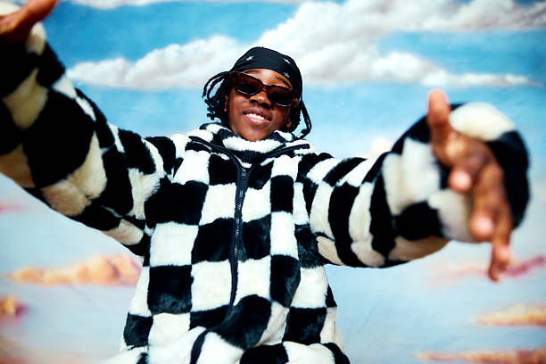 Child wearing a checkered faux fur jacket and sunglasses reaching towards the viewer, smiling