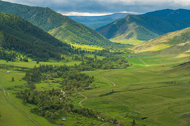 Wide green valley surrounded by mountain slopes and hills in natural landscape. Suitable for nature, countryside, and outdoor themes.