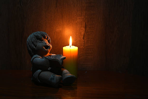 A statue of a boy reading a book with a candlelight