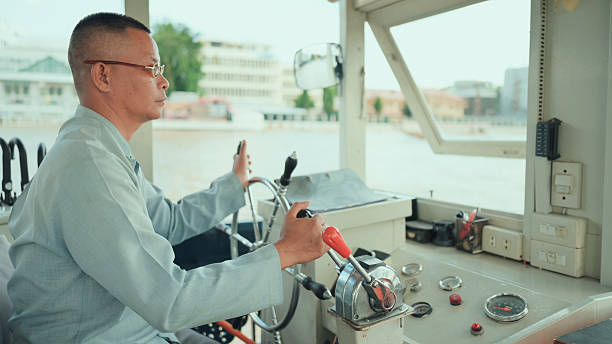 thai boat captain steering a passenger vessel with precision and calm experienced river operator navigating a ferry boat, highlighting daily work life, navigation skills, and the importance of river transport in local commuting systems.