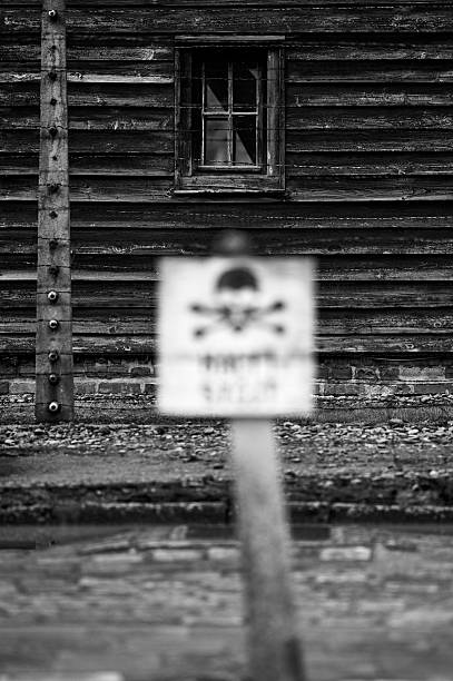Blurred warning sign and wooden barracks at Auschwitz camp