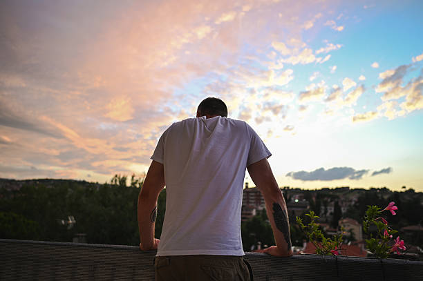 Man watching sunset over city skyline from a rooftop