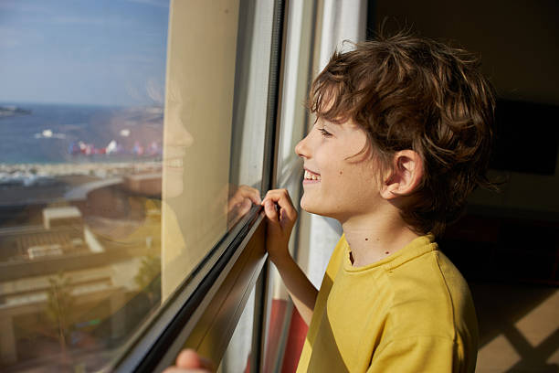 boy looks out the window at the beautiful forest nature.