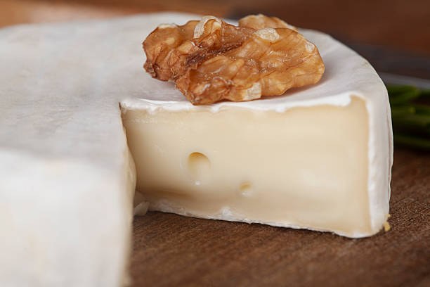 Organic farm camembert or brie cheese on a wooden board with rosemary and nuts close-up