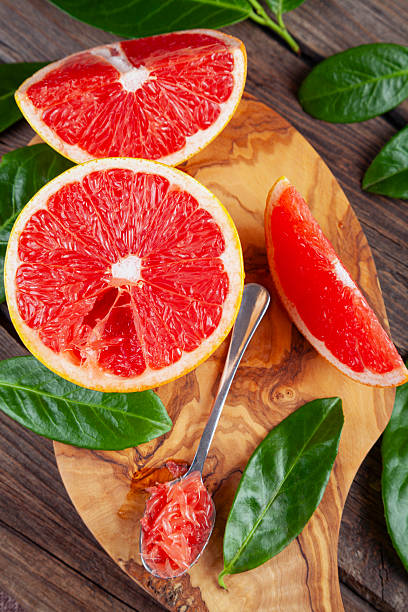 Grapefruits sliced on an olive cutting board on a rustic wooden table