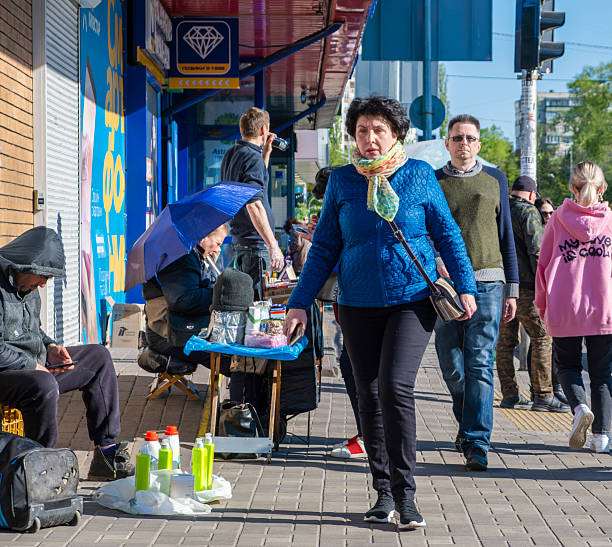 Kyiv, Ukraine - 12th May, 2022: People walking on a city sidewalk in the Livoberezhna area. Street vendors selling goods and individuals browsing products on a sunny day
