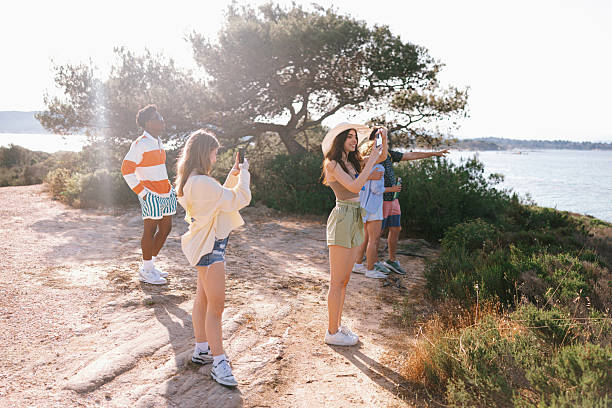 Male photographer taking a photo of a multiracial group of friends in the street