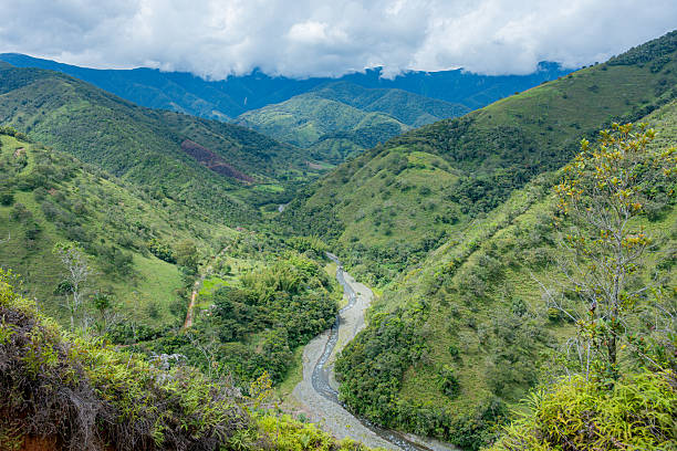 Green mountains and valleys featuring a winding river under a cloudy sky