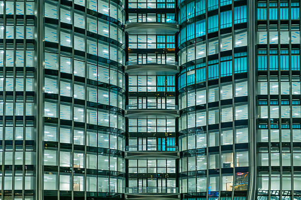 Modern glass office building facade at night with illuminated windows and repeating geometric pattern in Hong Kong city, China. Abstract architecture background. Close up.