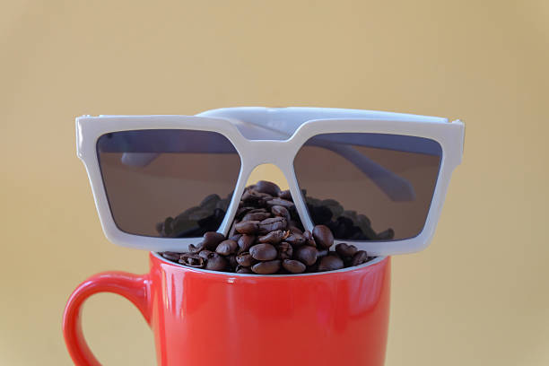 Coffee beans spill out of cup and sunglasses on color background.