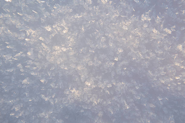 Close-up macro view of sparkling snow and ice crystals illuminated by soft natural light. Abstract winter background texture ideal for concepts such as cold, purity, freshness, winter, frost, climate, and seasonal design.