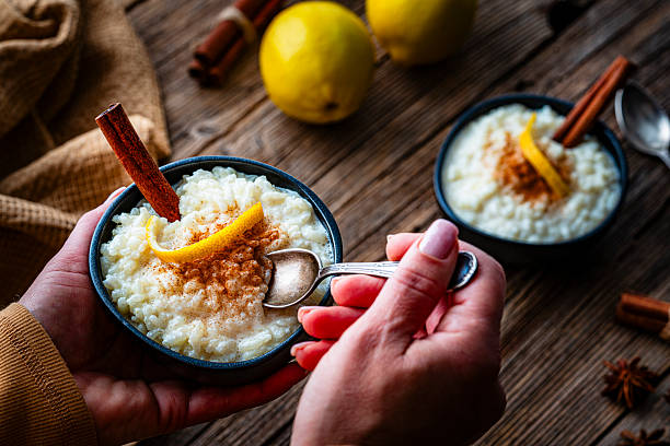 Sweet food: unrecognizable person eating homemade rice porridge or pudding with cinnamon stick