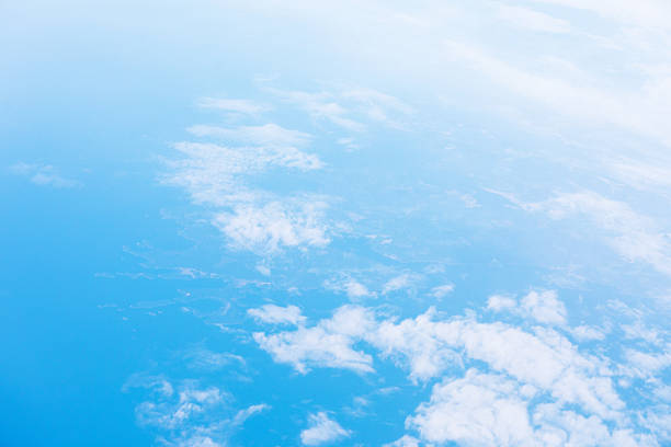 Tranquil aerial view reveals scattered white clouds drifting above vast blue expanse ocean. Scene captures Earth serene atmosphere and peaceful rhythm of nature from above