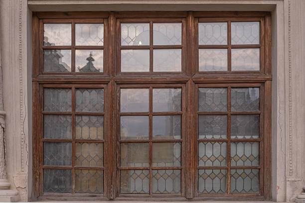 Large brown wooden multipane window with patterned leaded glass on a historic facade. Lviv, Ukraine.