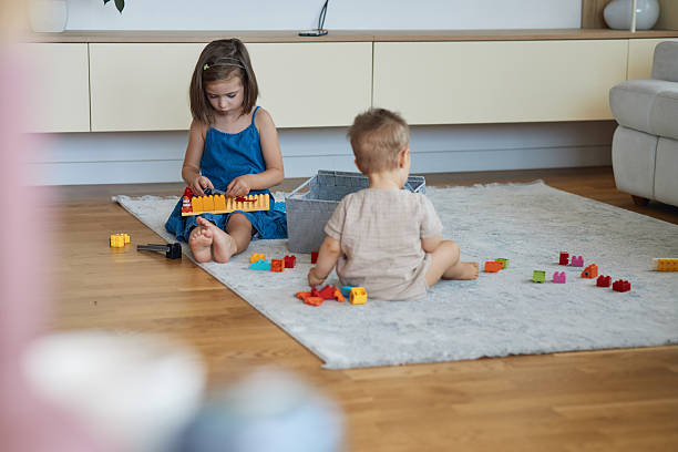 Two young children engrossed in playing construction toys on a carpet in their modern home