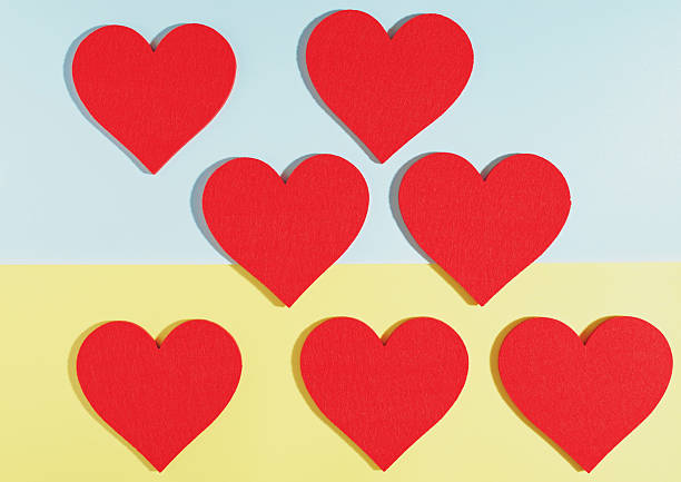 Arrangement of red hearts forming a simple pattern on a pastel blue and yellow color-block background, leaving clean copy space for a campaign headline or greeting. Works for Valentine’s Day, Mother’s Day, or healthcare communication focused on care and heart health. Warm, supportive mood.
