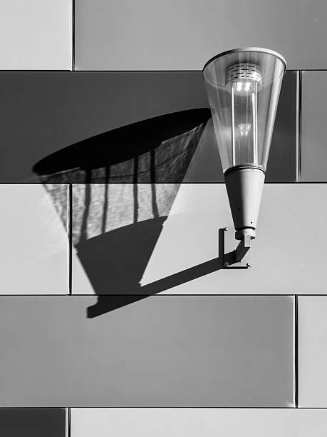 old rusty lamppost on a white wall with its shadow cast on it