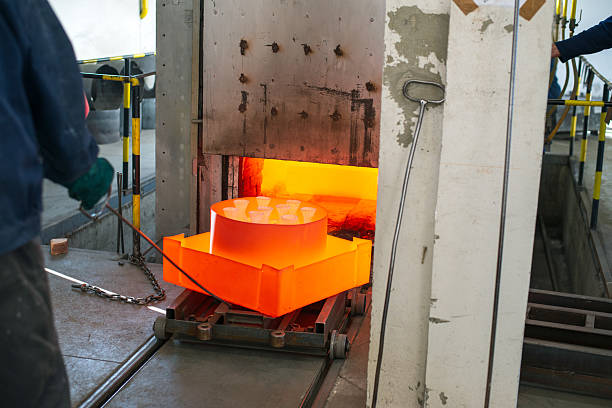 Blue collar metal worker working with the red-hot steel casts in the modern foundry.