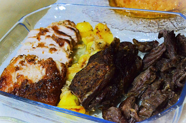 A glass dish containing beef and pork roasted in the oven with baby potatoes.