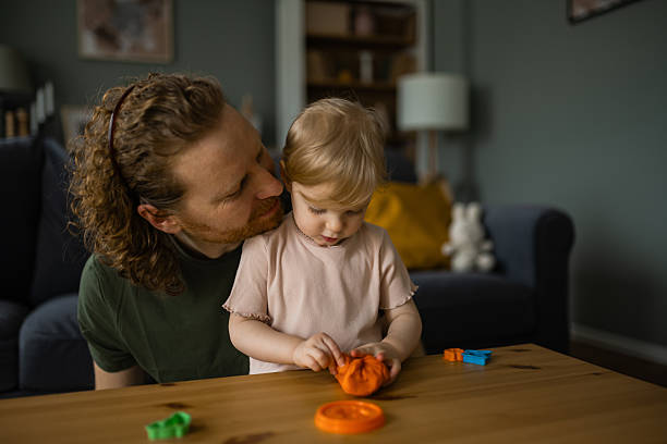 Father and young daughter creating shapes with colorful modeling clay together