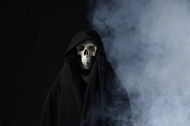 Creepy ghost. Skeleton covered with sheet in smoke on black background