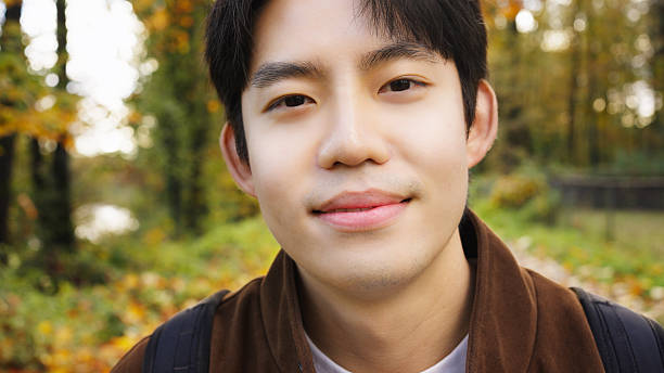 Close-up of young asian man smiling at camera during a relaxing autumn hike