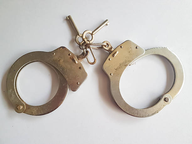 a pair of steel handcuff swith two keys on white isolated background
