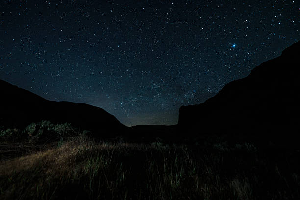 Stars shine brightly over a remote desert canyon, capturing the peaceful atmosphere of nighttime camping in Central Oregon.