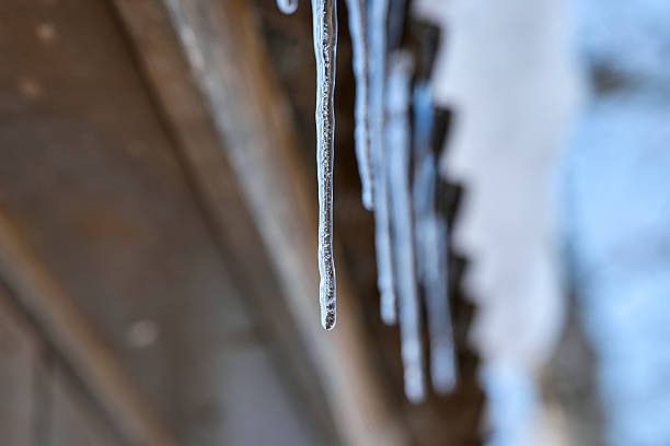 Icicle photographed against the sky. Long icicle with selective focus. Winter. Frosty weather. Frozen icicles in winter, close-up