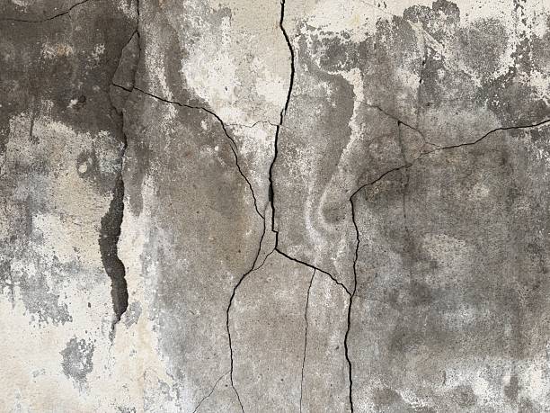 Cracks on the orange plaster wall. Cracked wall. Wall damage close-up, background, texture.